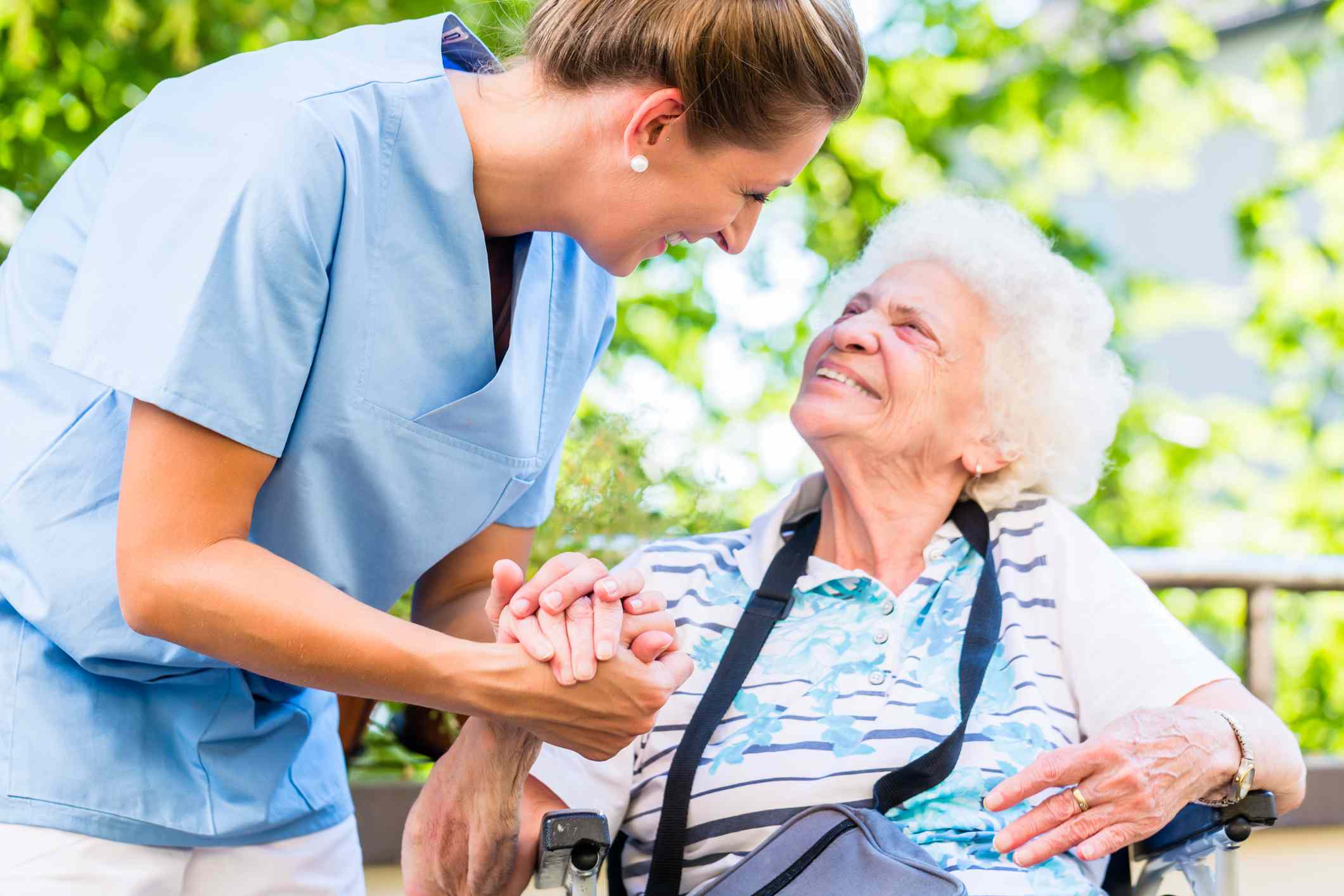 A caregiver speaking with an older woman outdoors.